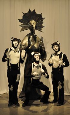 three men in costume standing next to a statue