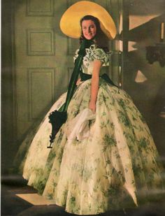 an old photo of a woman in a dress and hat wearing a large yellow hat