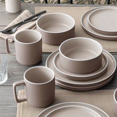 a table set with plates, cups and utensils on top of a placemat