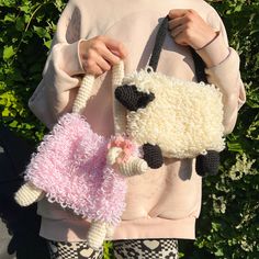 a woman holding two knitted sheep purses