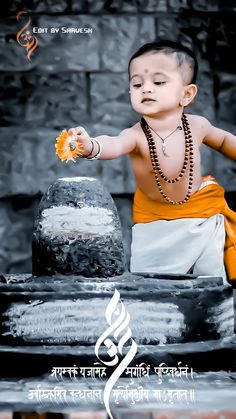 a little boy sitting on top of a table next to a vase filled with flowers