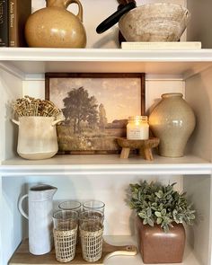 shelves with vases, candles and other items on them in a living room area