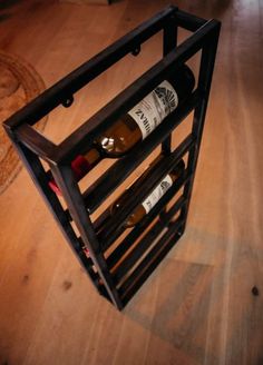 a wine rack holding two bottles on top of a wooden floor next to a rug