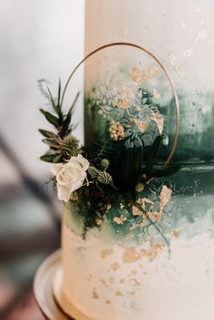 a close up of a cake with flowers on it and greenery in the middle