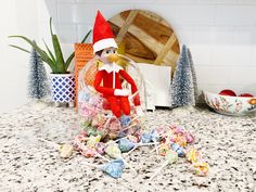 an elf is sitting on the counter next to some candy