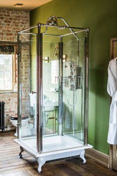 a bathroom with a stand up shower in the corner and wooden flooring on the other side