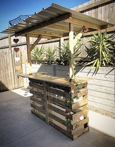 an outdoor bar made out of pallets with plants growing on the top and bottom