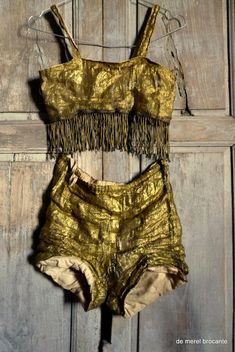 two pieces of gold colored clothing hanging on a wooden door with the bottom part cut off