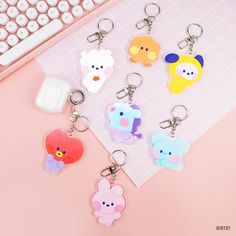 four keychains with different cartoon characters on them sitting next to a computer keyboard