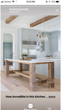 a kitchen with an island in the middle and wooden beams on the ceiling above it