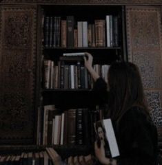 a woman standing in front of a book shelf filled with books