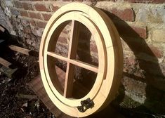 a circular wooden window sitting next to a brick wall