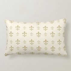 a white and gold pillow with fleur de lis pattern on it's side