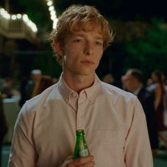 a young man is holding a beer in his hand