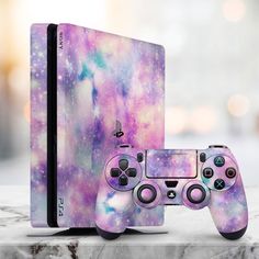 a video game console and controller sitting on top of a marble surface with colorful paint