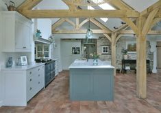 a large kitchen with an island in the center and wooden beams on the ceiling above it