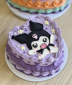 two decorated cakes sitting on top of a wooden table