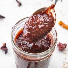 a spoon full of jam on top of a jar