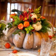 an arrangement of pumpkins and flowers on a table