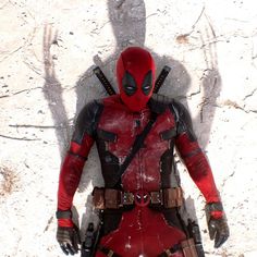 deadpool standing in front of a rock wall with his shadow on the wall behind him