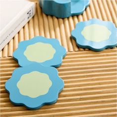 three blue flower shaped coasters sitting on top of a bamboo mat