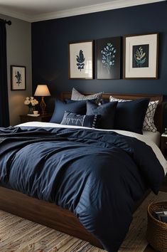 a bedroom with dark blue walls and white bedding in the center, along with two framed pictures on the wall