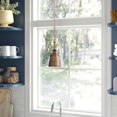 a kitchen with blue walls and open shelves on either side of the window is a sink