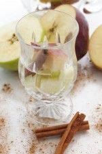 an apple cider with cinnamon sticks and apples in the background on a white surface