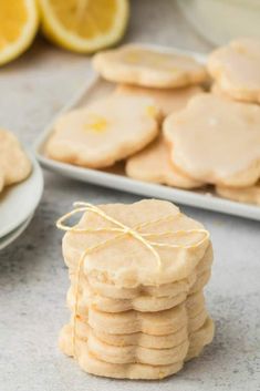 lemon cookies are stacked on top of each other in front of plates with lemons