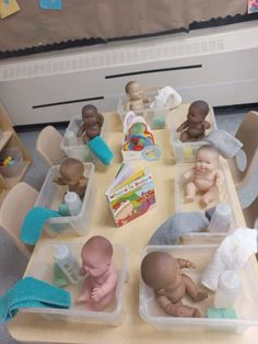 there are many baby dolls in plastic containers on the table