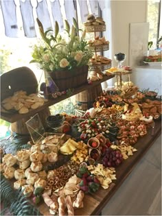 an assortment of food is displayed on a table in a room with white walls and wooden flooring