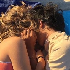 two people laying in the sand with their backs to each other and one person covering his face