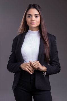 a woman in black pants and a white top is posing for the camera with her hands on her hips