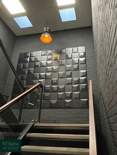 an empty stairwell leading up to a wall with geometric tiles on it and a yellow light hanging from the ceiling