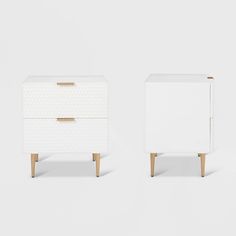 two white nightstands side by side with wooden legs and handles, one in the foreground