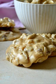 two cookies with peanut butter frosting in front of a bowl full of cookies on the table