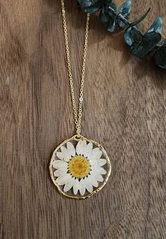 a white and yellow flower on a gold chain