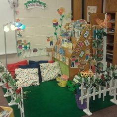 a room filled with lots of different items and flowers on the floor next to bookshelves