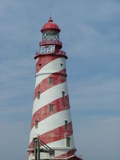 a large red and white lighthouse sitting on top of a beach