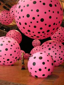 large pink and black polka dot balloons in an indoor space with people standing on the floor