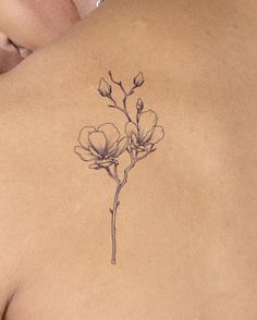 the back of a woman's shoulder with a flower tattoo on her left side