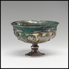 a silver and green bowl with designs on it