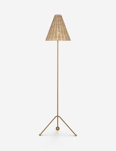 a floor lamp with a beige shade on the top and a gold metal tripod base