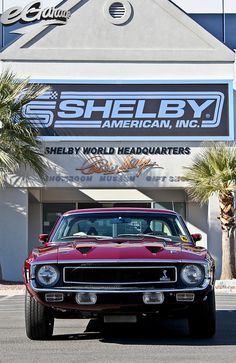 a red car is parked in front of a shell by american, inc storefront