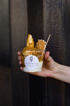 a hand holding a small cup filled with honeycombs and topped with a stick