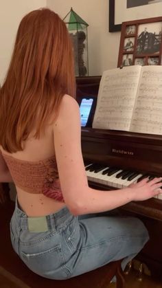 a woman sitting on the floor playing a piano with music sheets in front of her