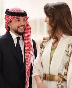 a man in a suit shaking hands with a woman wearing a red and white headdress