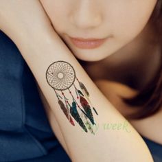 a woman with a tattoo on her arm that has a dream catcher design on it