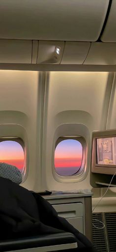 the view from inside an airplane looking out at the sunset through the window and on to the back of the seat