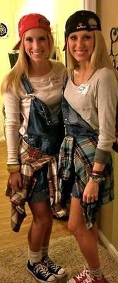 two young women standing next to each other in front of a door wearing hats and overalls